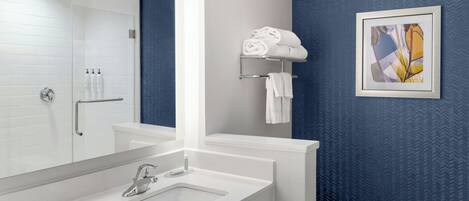 Un baño moderno con un lavabo blanco, un espejo, un inodoro y un perchero para toallas.