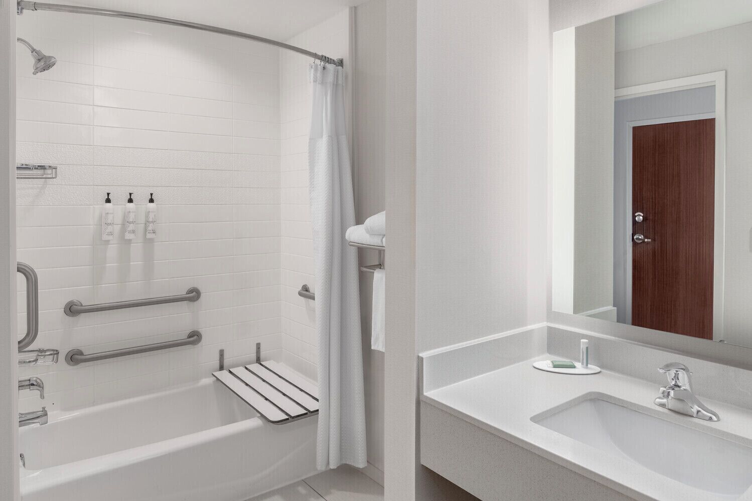 Een moderne badkamer met een inloopdouche, handgrepen, een wastafelmeubel en een spiegel.