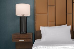 Een hotelkamer met een bed, een nachtkastje met een lamp en een gestructureerde muur.