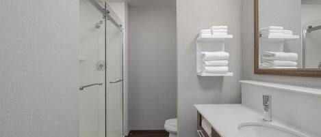 A modern bathroom with a glass shower enclosure, a white sink, and a mirror with a wooden frame.