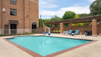 Una piscina al aire libre de temporada, sillones reclinables de piscina