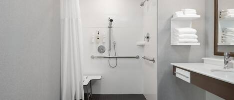 Une salle de bain moderne avec une douche, des toilettes et un lavabo. Des serviettes et des articles de toilette sont disposés sur le mur.