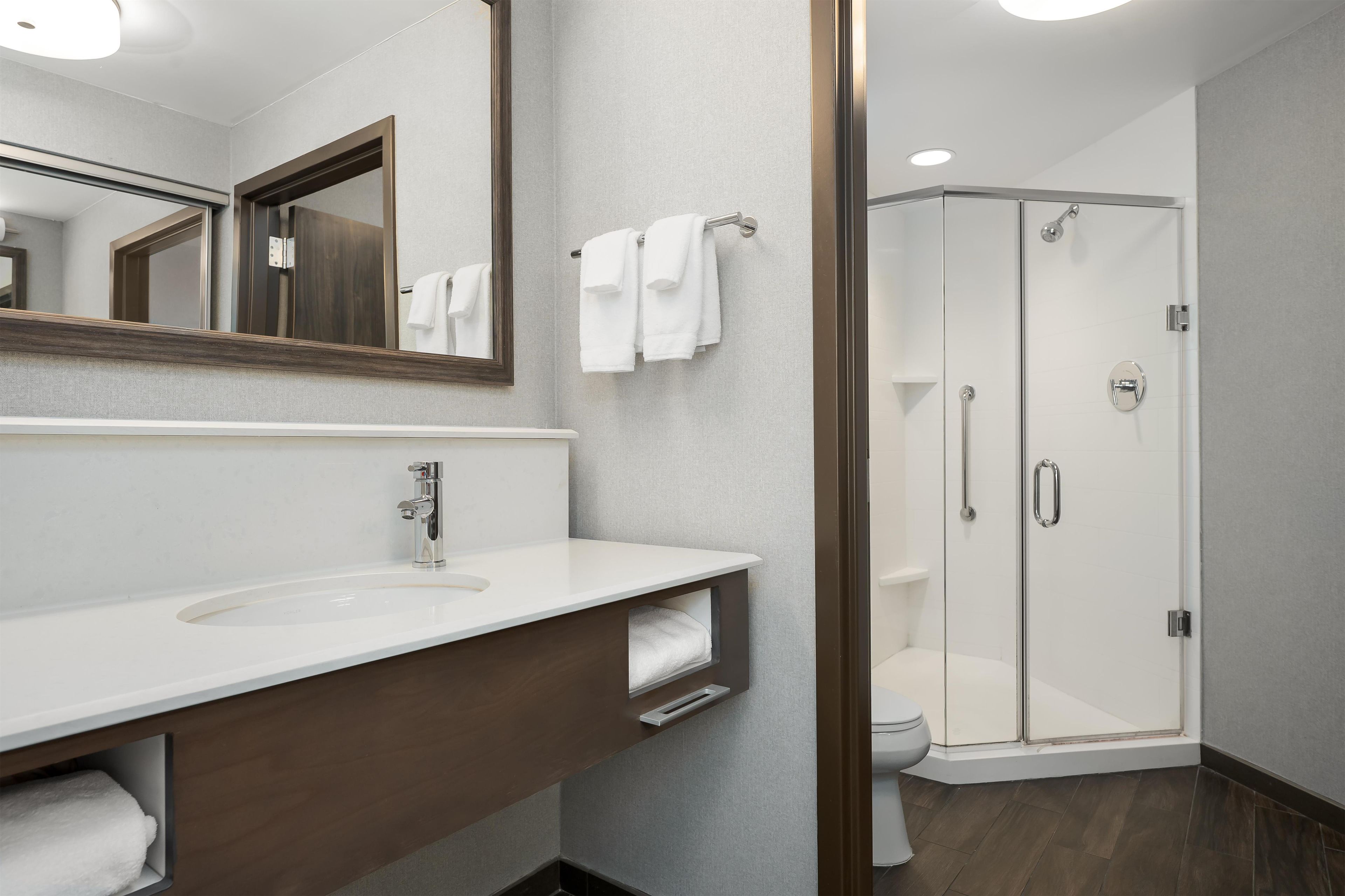 A modern bathroom with a white sink, a mirror, and a glass-enclosed shower.