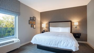 A hotel room with a large bed, two bedside lamps, a window with a view, and a wall-mounted heater.