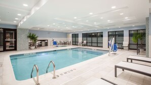 A swimming pool with clear lane markings, adjacent lounge chairs, and a modern ceiling design. - Hampton Inn Rochester Penfield (Rochester)