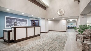 A hotel reception area with a reception desk, a large framed picture, and a seating area with chairs. - Hampton Inn Rochester Penfield (Rochester)