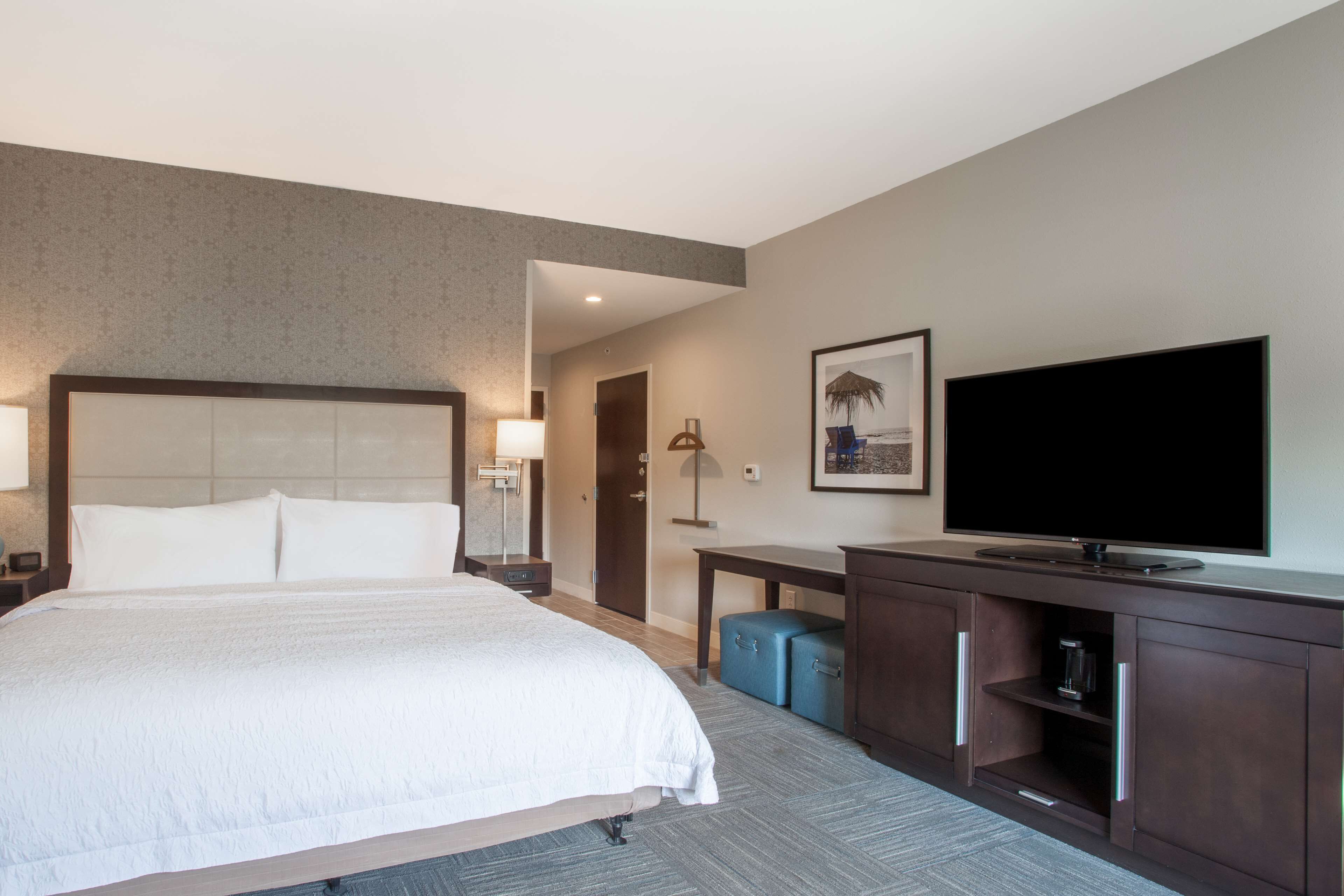 A hotel room with a large bed, a flat-screen TV, a desk, and a wardrobe.