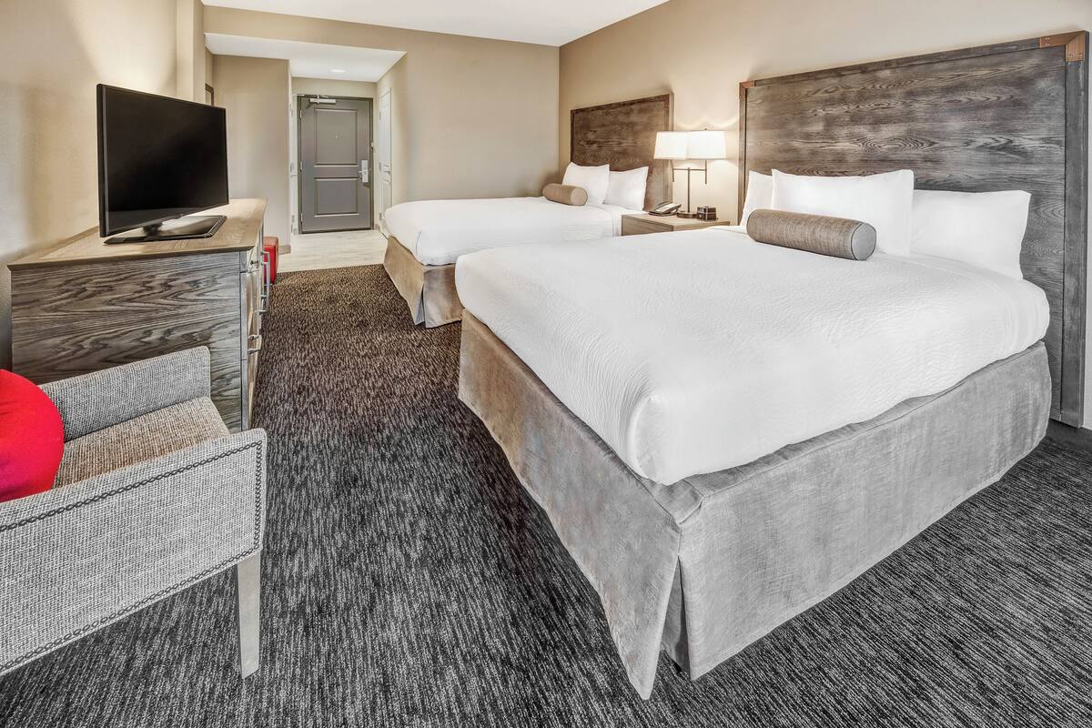 Una habitación de hotel con dos camas, televisión, escritorio y silla.