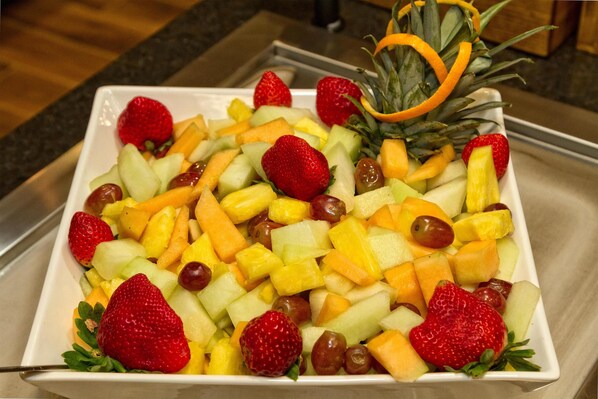 A square white plate filled with a variety of fruits including strawberries, grapes, and pineapple.