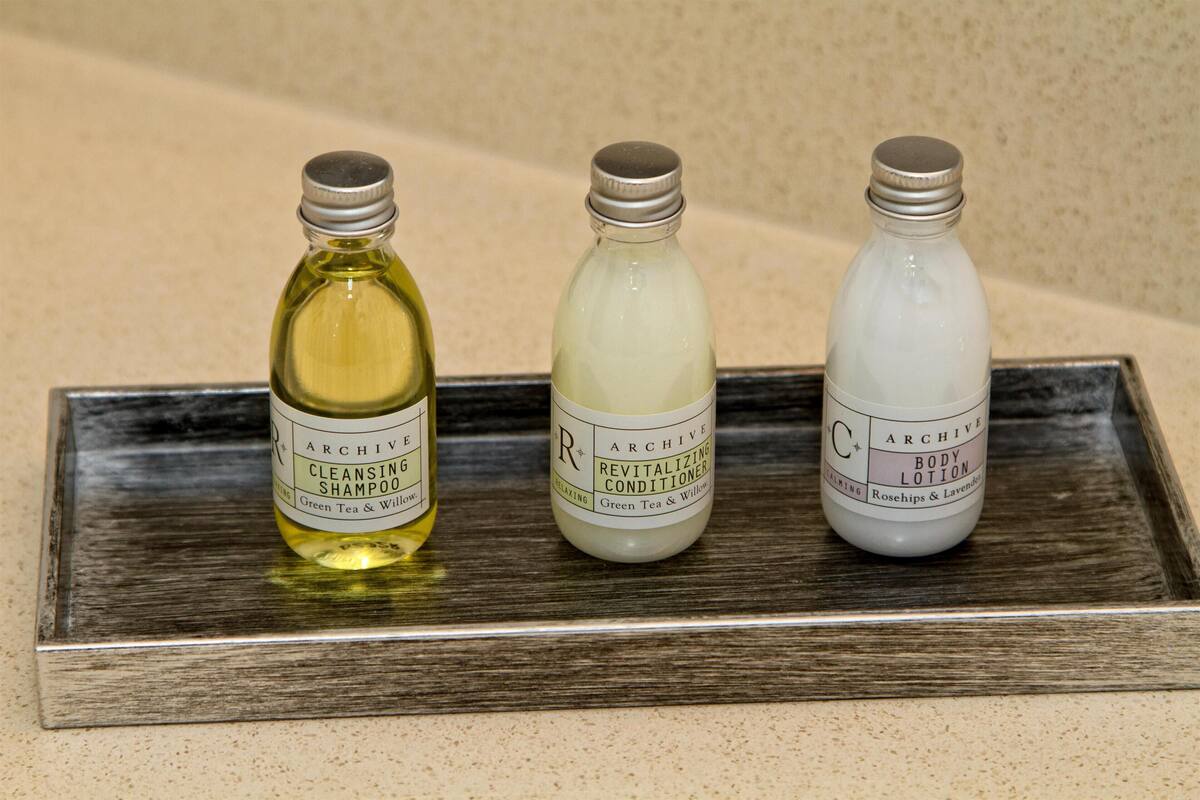 Tres botellas de productos de cuidado corporal Archive sobre una bandeja.