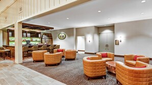 Un hall d’entrée spacieux avec un bar, des sièges confortables et une grande horloge au mur.