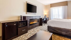 A hotel room with a bed, a flat-screen TV, a mini-fridge, a microwave, and a fireplace. - Sleep Inn & Suites Middletown - Goshen (Middletown)