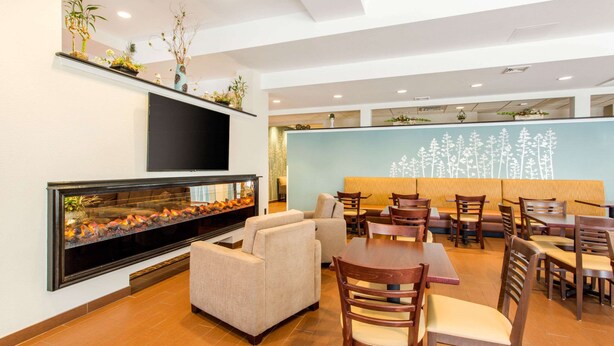 A modern dining area with a large fish tank, sofas, and wooden tables and chairs. - Sleep Inn & Suites Middletown - Goshen (Middletown)