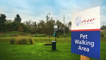 A sign for a Pet Walking Area with a logo for Paw Pets Are Welcome.