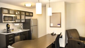 Een moderne keuken met een eettafel, stoelen, een koelkast, magnetron en koffiezetapparaat.