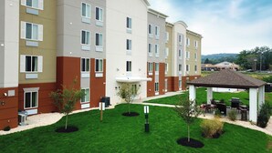 A multi-story hotel with a central courtyard, outdoor seating area, and a covered gazebo. - Candlewood Suites York by IHG (York)