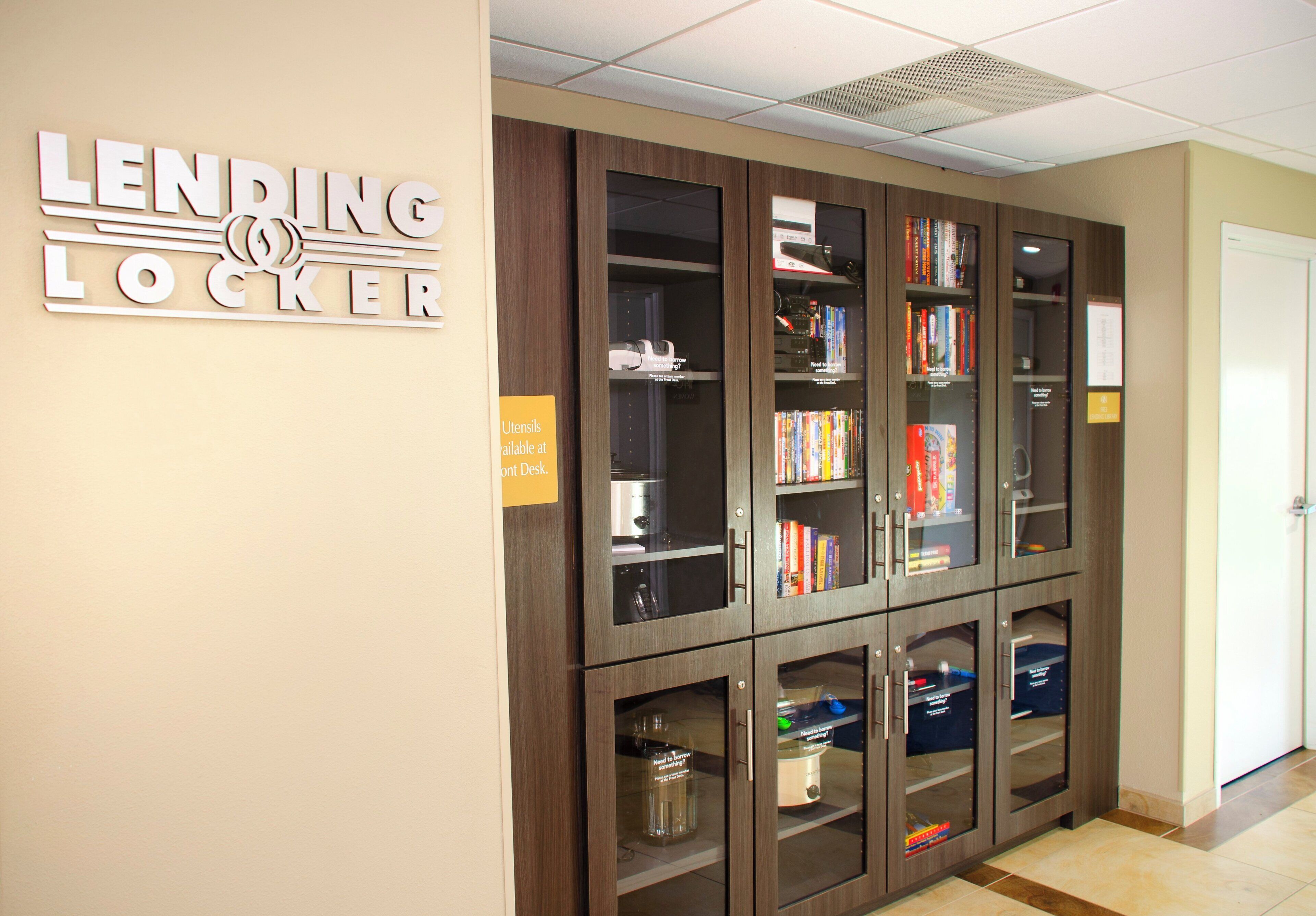 A lending locker area with bookshelves and a sign indicating the availability of utensils at the front desk.