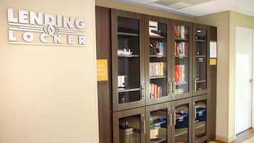 A lending locker area with bookshelves and a sign indicating the availability of utensils at the front desk.