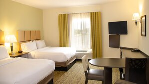 Een hotelkamer met twee bedden, een bureau, een stoel, een televisie en een raam met gordijnen.