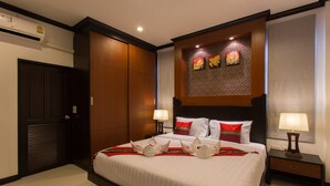 A hotel room with a large bed, two bedside tables with lamps, a wall-mounted artwork, and a door with a security shutter. - The Best Aonang Villas (Krabi)