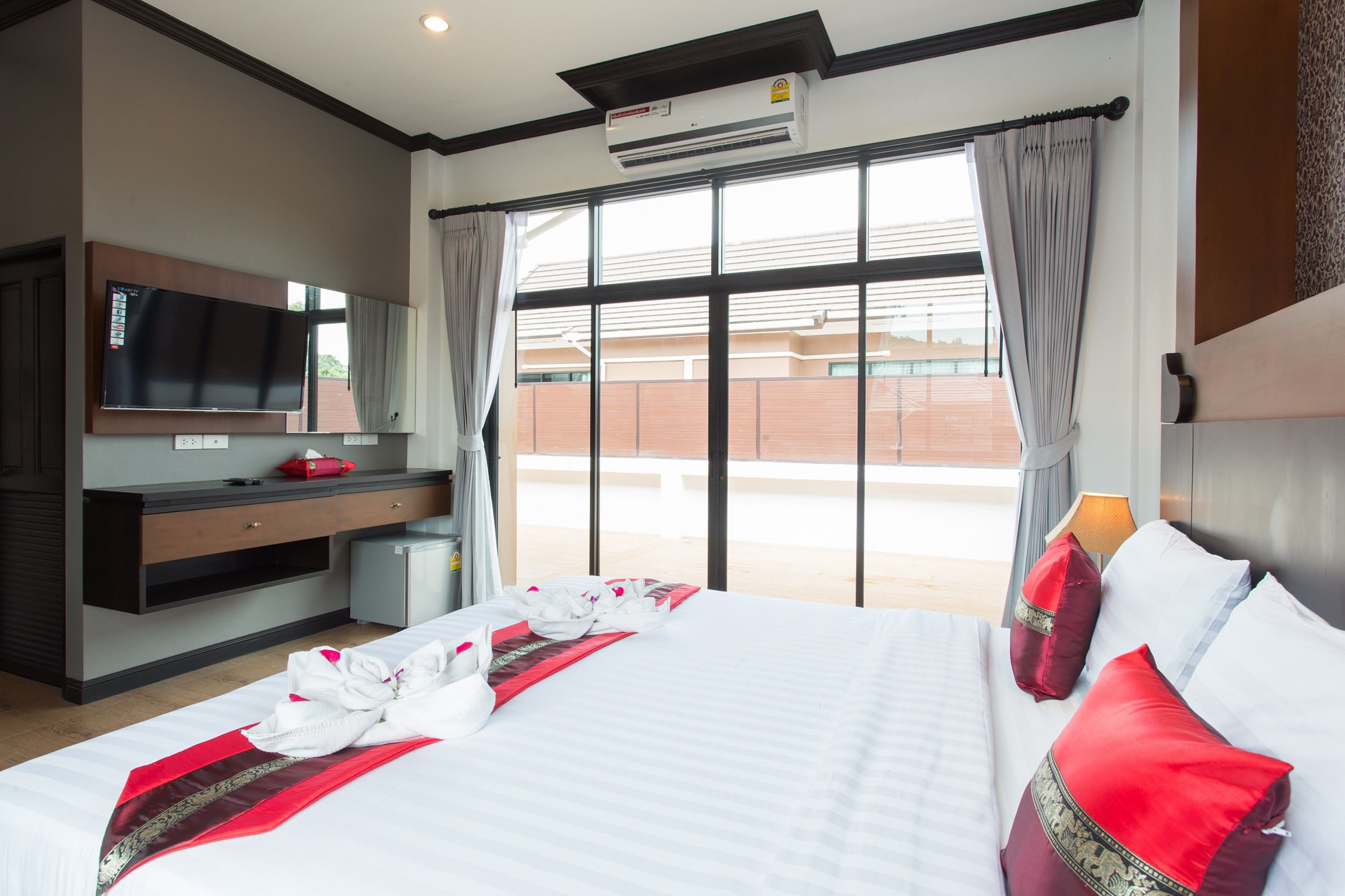 A hotel room with a large bed, a flat-screen TV, a desk, and a window with curtains.