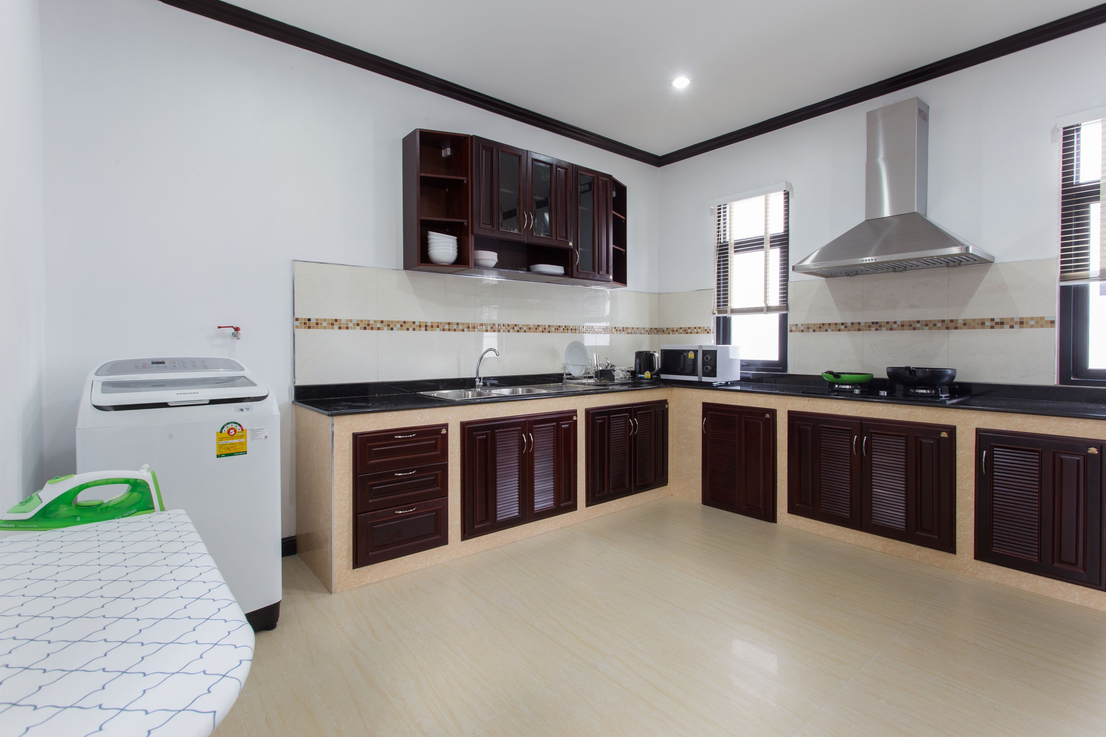 A modern kitchen with dark wooden cabinets, a stainless steel range hood, and a built-in oven.