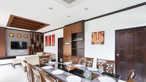 A dining area with a long table set for six, surrounded by wooden chairs. - The Best Aonang Villas (Krabi)