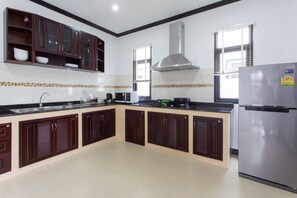 Una cocina moderna con armarios de madera oscura, un refrigerador de acero inoxidable y un salpicadero de azulejos.
