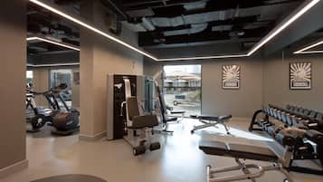 A gym with exercise equipment, a treadmill, and dumbbells.