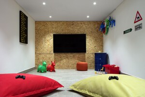 A room with a large TV mounted on a wooden wall, two bean bags, and a few toys.