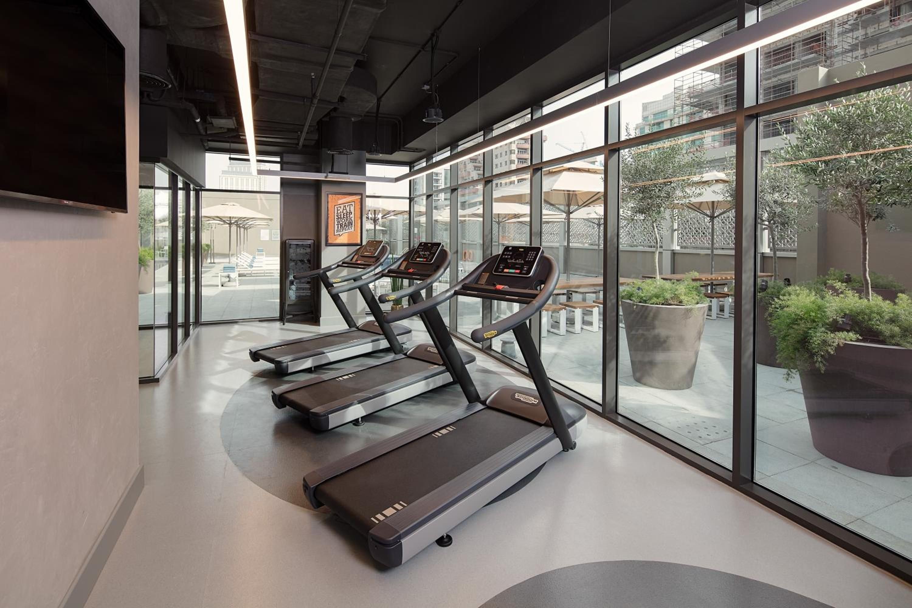 A gym with treadmills, large windows, and a view of the outside.