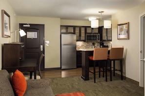 A compact kitchen with a refrigerator, microwave, and bar stools. - Staybridge Suites Columbus Polaris by IHG (Columbus)