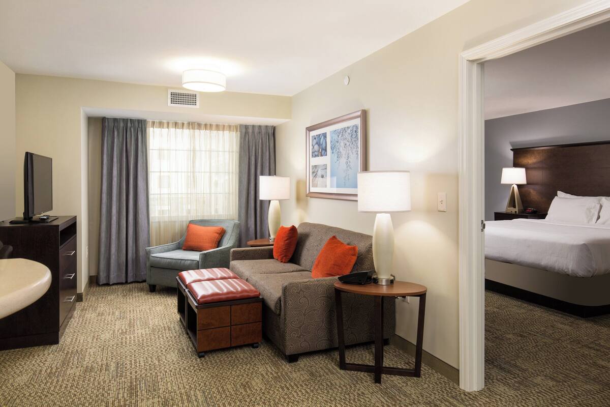 A hotel room with a bed, a sofa, a desk, and a television.