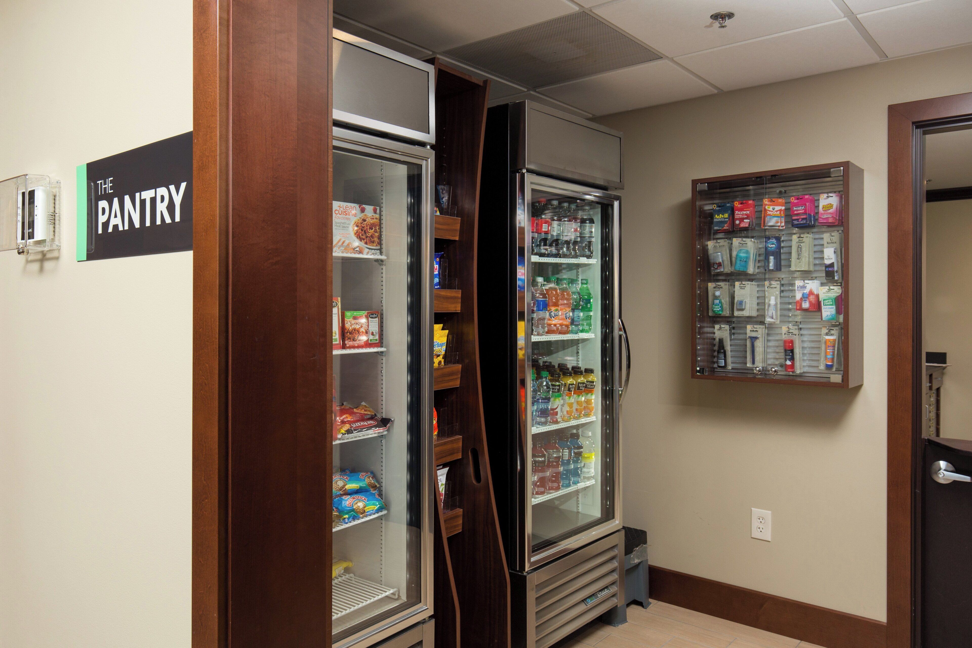 Uma área de despensa com prateleiras refrigeradas e não refrigeradas, abastecida com diversos alimentos e bebidas.