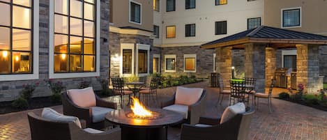 A courtyard with outdoor seating, a fire pit, and a stone building with multiple windows.