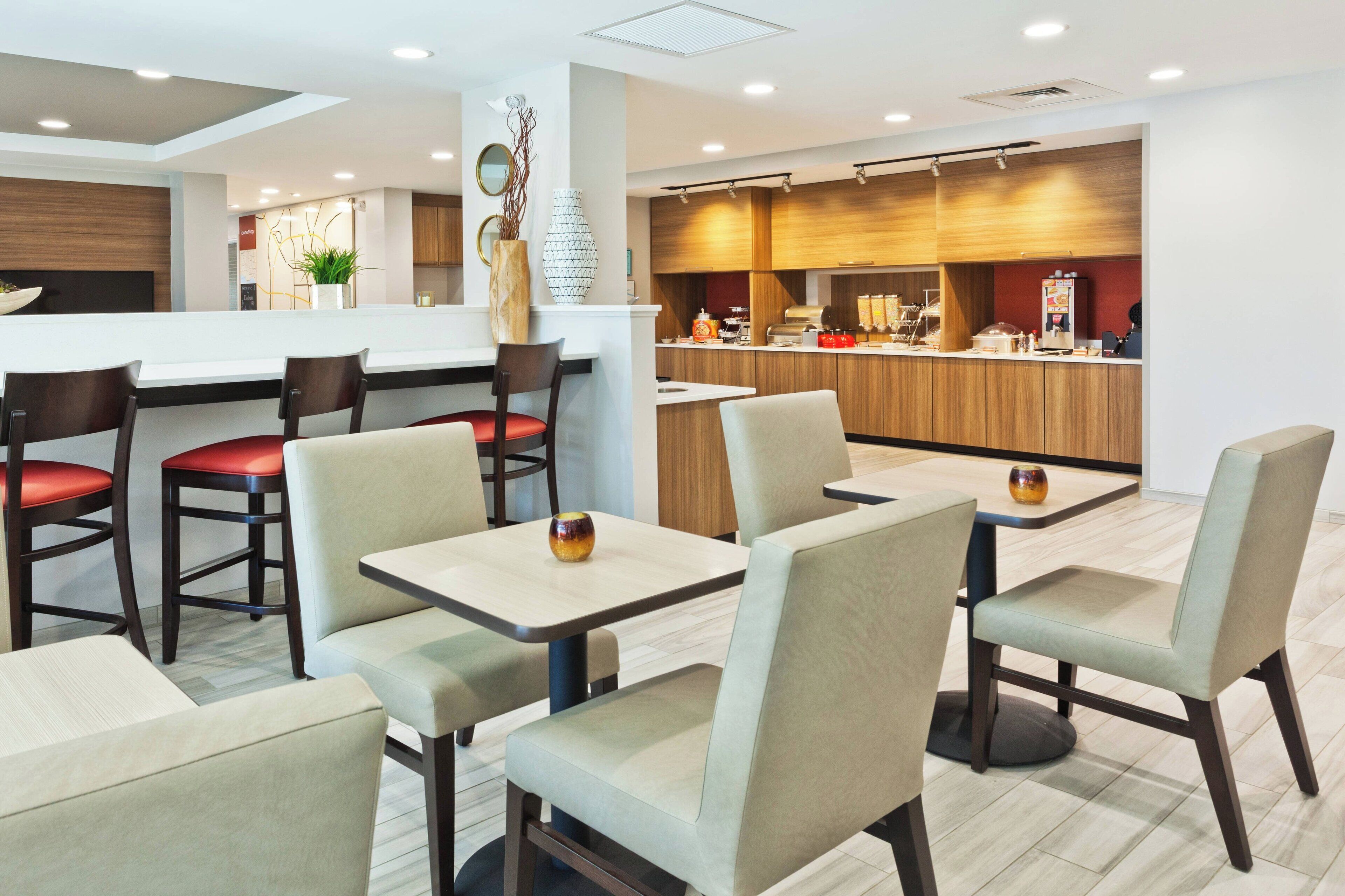Un restaurante moderno con una zona de bar, asientos con sillas acolchadas y un diseño limpio y contemporáneo.
