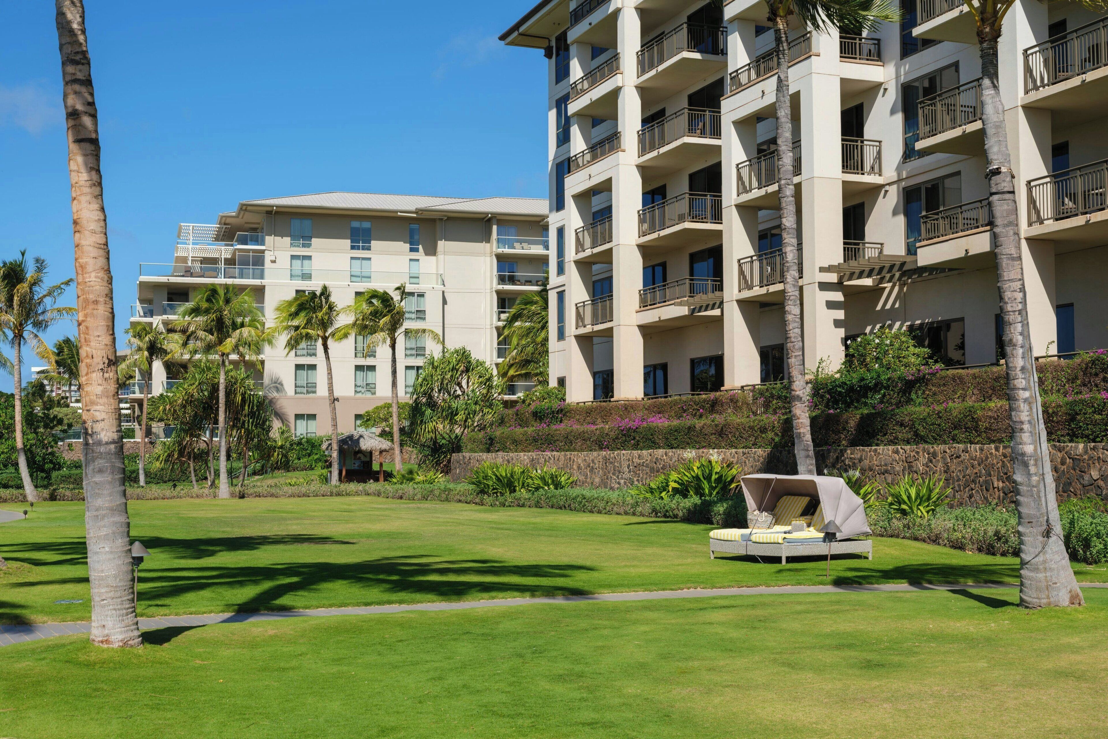 Un hotel con varios pisos, mobiliario exterior y palmeras.