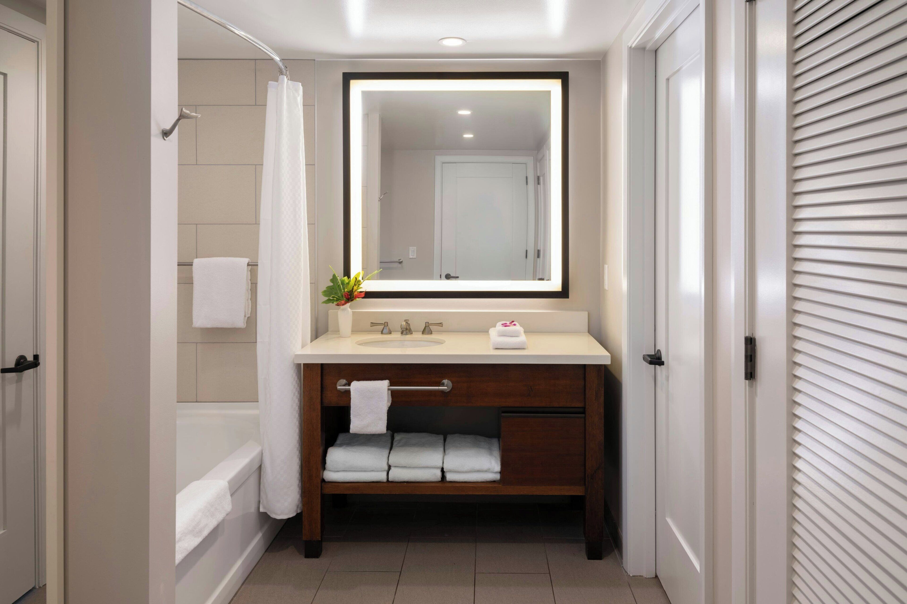 Une salle de bain avec une baignoire, un meuble-lavabo avec un miroir et un porte-serviettes.