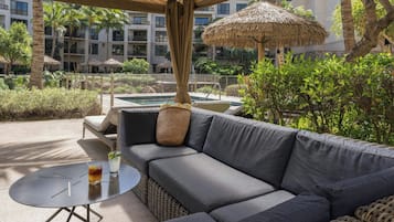 Zona junto a la piscina con un sofá, una mesa redonda y una bebida.