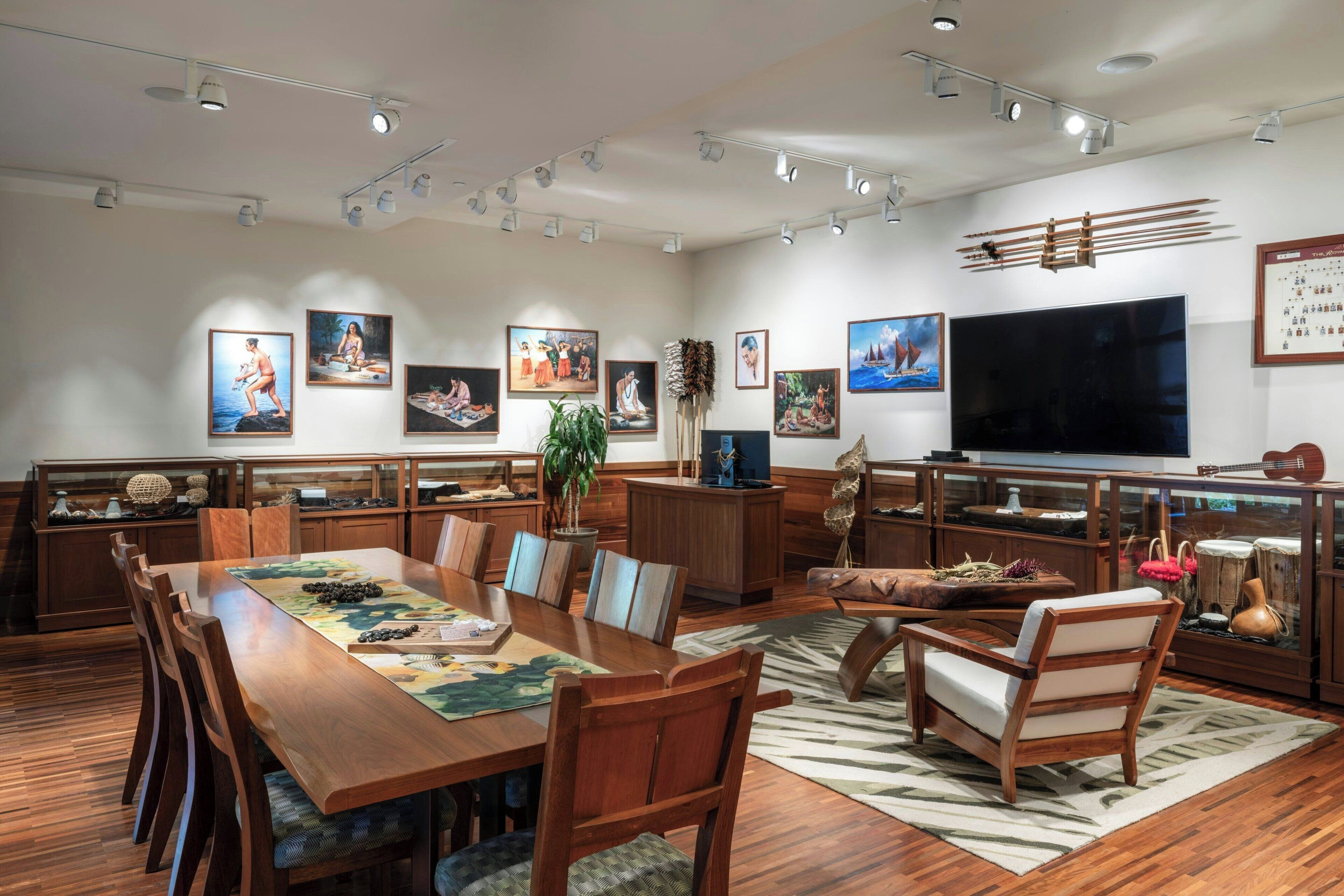 A spacious dining area with a long wooden table, multiple chairs, and a large flat-screen TV mounted on the wall.