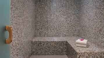 A bathroom with mosaic tile walls and a wooden door handle.