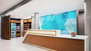 A modern reception area with a wooden reception desk, a large digital display, and a vending machine.