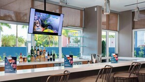A modern bar area with a flat-screen TV, bar stools, and a glass display case with bottles.