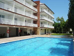 A multi-story hotel with balconies, a swimming pool, and outdoor seating.