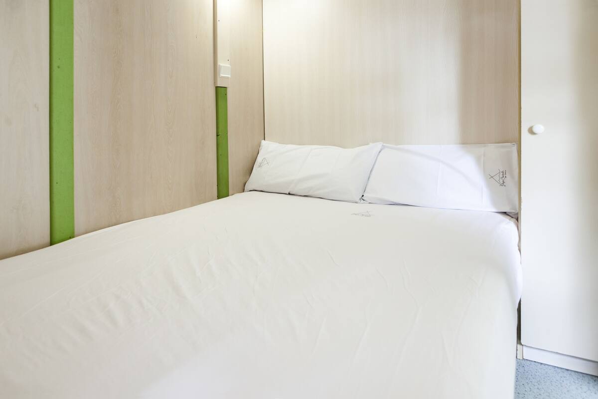 A single-bed room with a wooden headboard and a green accent wall.