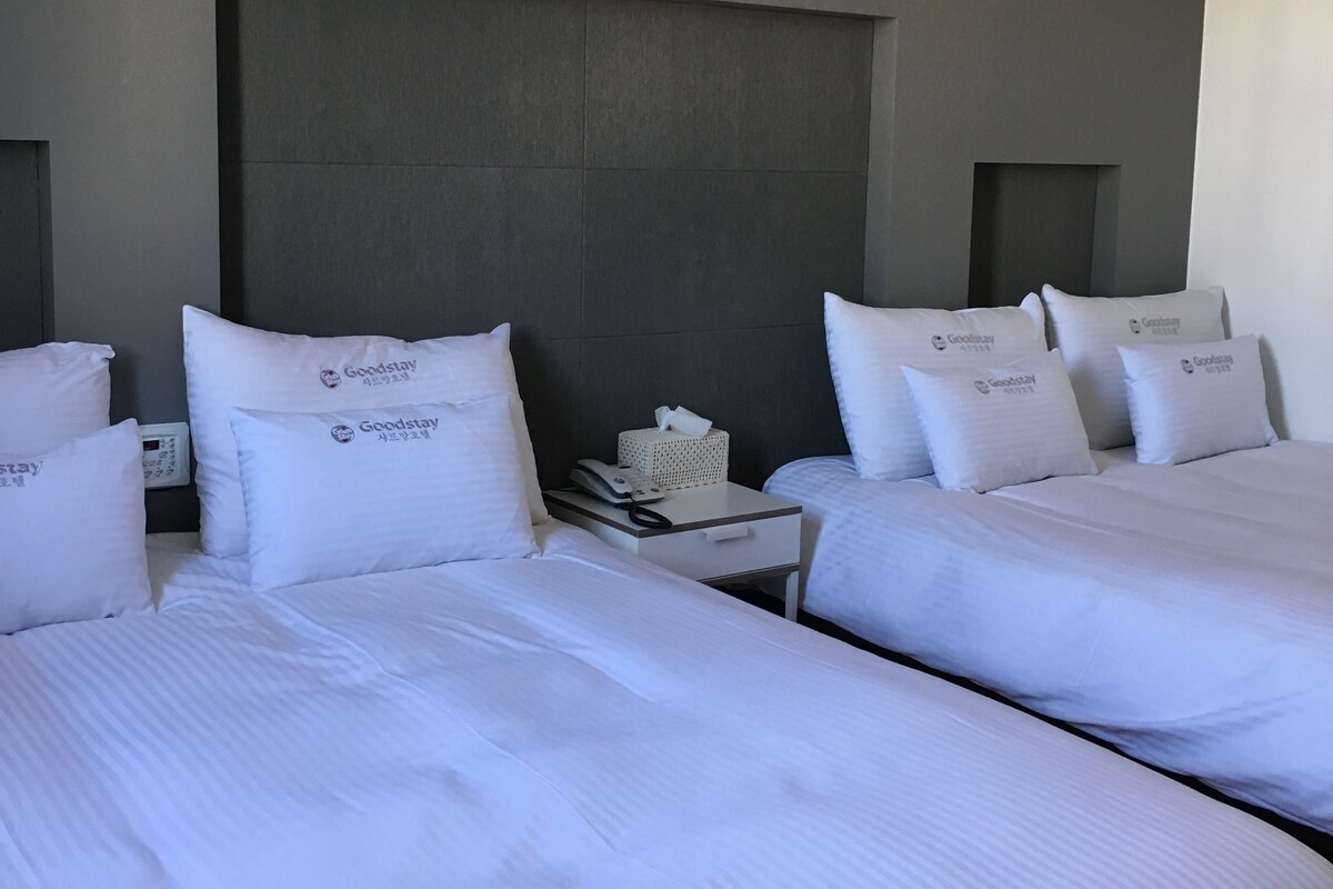 A hotel room with two beds, white bedding, and a headboard.