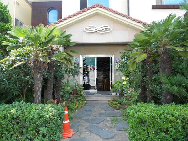 A building with a tiled roof and a sign with a stylized infinity symbol. - Charmant Hotel (Mokpo)