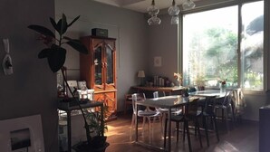 A modern dining area with a wooden table and chairs, a cabinet with glass doors, and a large window providing a view of the outdoors. - Charmant Hotel (Mokpo)