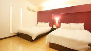 A hotel room with two beds, a red accent wall, and a nightstand with a lamp. - Charmant Hotel (Mokpo)
