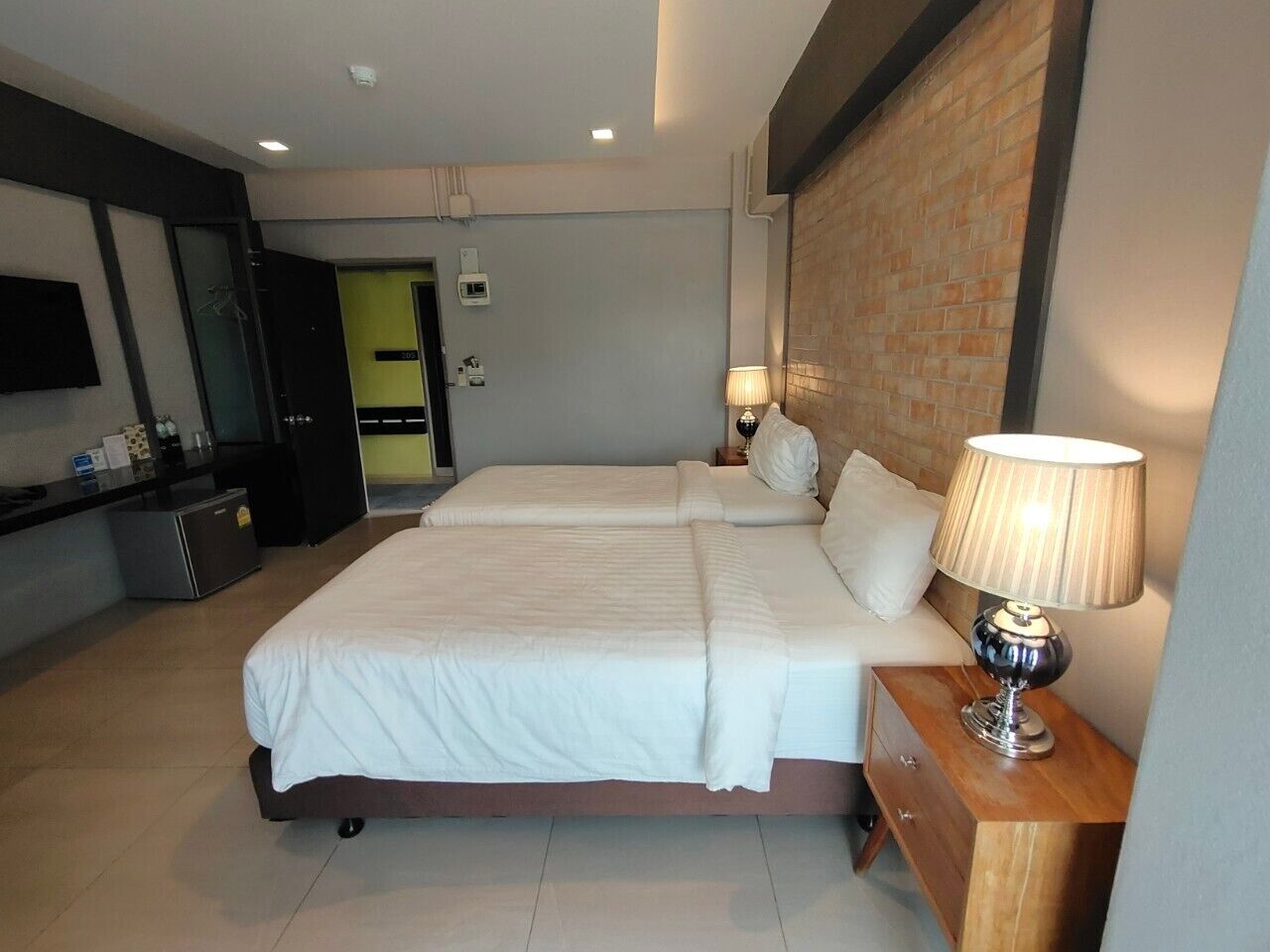 A hotel room with a large bed, a bedside table with a lamp, a small desk, and a mirror.